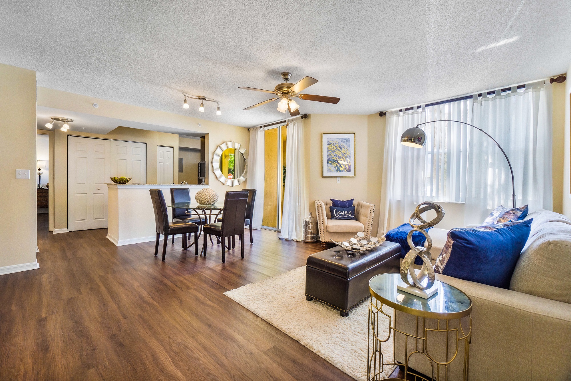 A living room with a brown wooden floor and a white ceiling fan.